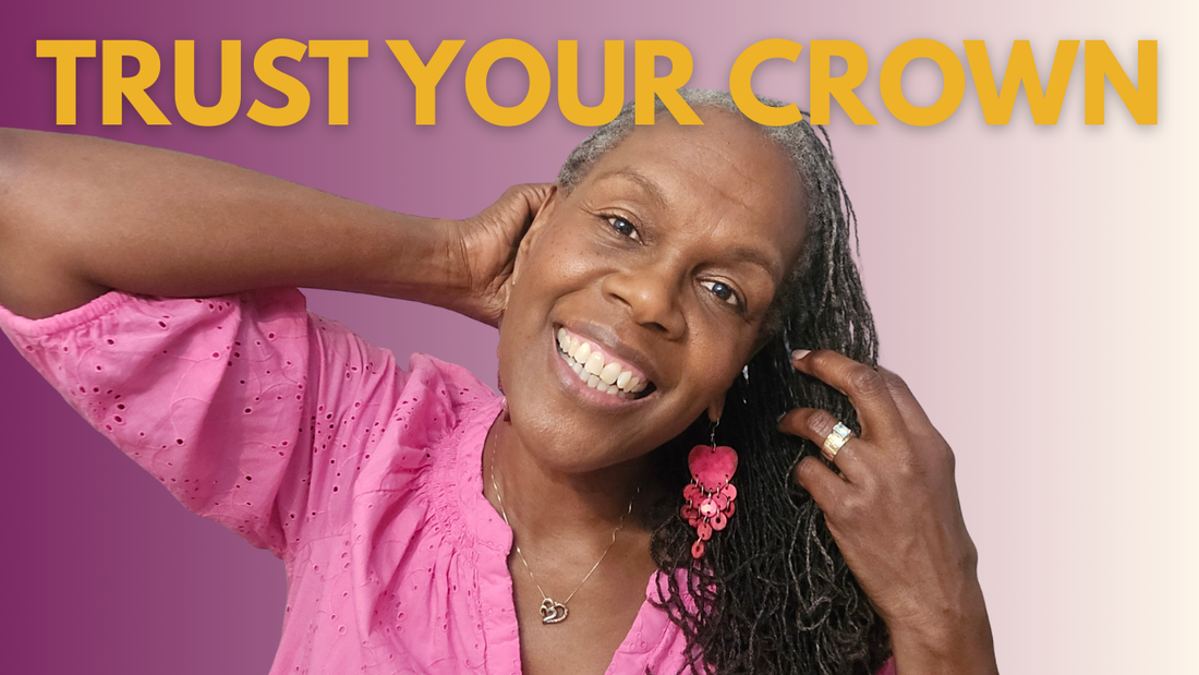 Older Black woman with gray Sisterlocks smiling pink blouse plum color background